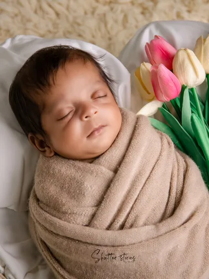A classic and clean setup with a neutrally wrapped baby and a bouquet of tulips, adding a fresh, gentle touch of color.