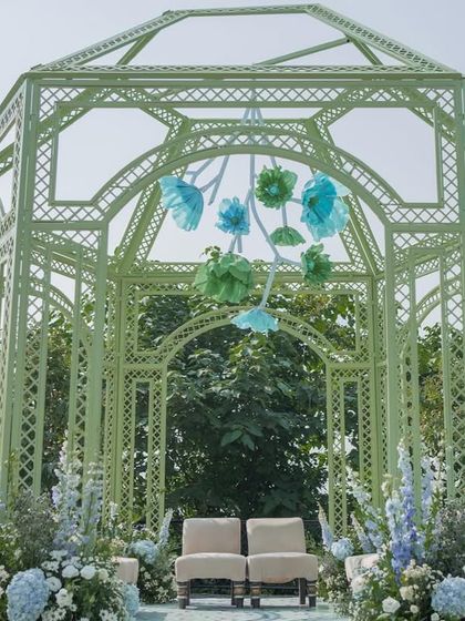 A closer look at the mint green mandap, adorned with a hanging installation of handcrafted paper flowers in shades of blue and green.