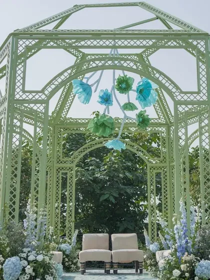 A closer look at the mint green mandap, adorned with a hanging installation of handcrafted paper flowers in shades of blue and green.