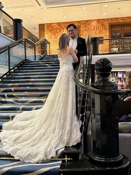 A classic fairytale moment. Our white lace wedding gown with a long train pairs perfectly with a timeless black tuxedo.