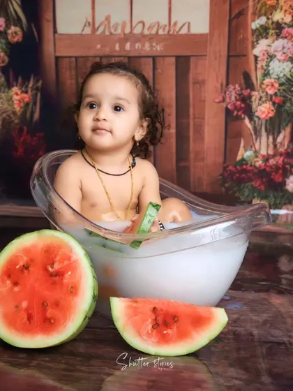 A sweet and curious look from the baby girl in her watermelon milk bath.