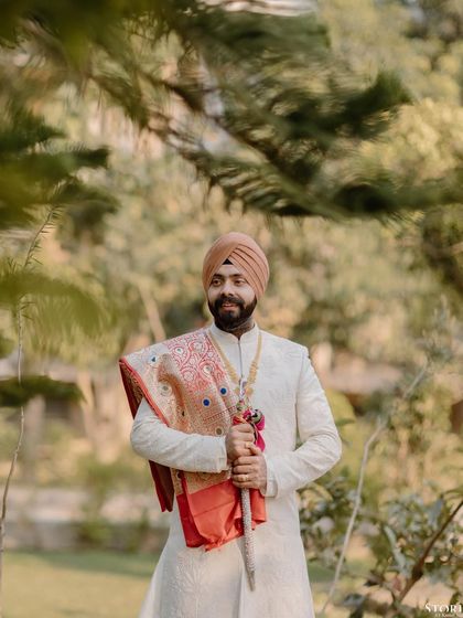 A portrait of the Sikh groom, Bimaljeet, holding the kirpan, looking regal and ready for the ceremony.