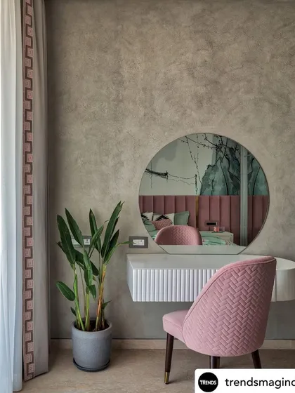 A close-up of a minimal dressing unit, showing the reflection of the bedroom in the mirror. The details, like the textured wall and pink chair, create a cohesive and stylish corner.