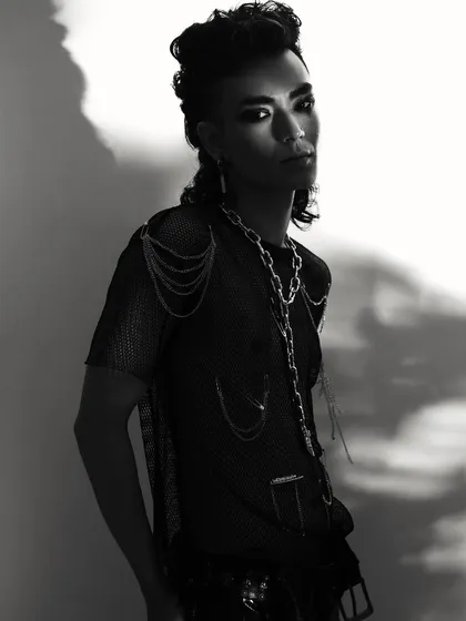 A full-body shot that showcases the complete punk-inspired look, with layered chains and a mesh top. The high-contrast lighting creates a strong silhouette.