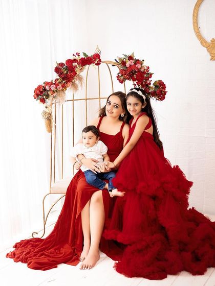 A stunning portrait of a mother with her two children. The coordinating red outfits and elegant studio props create a truly memorable family photo.