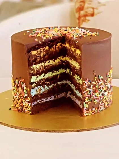 A fun and surprising rainbow cake with layers of colorful sponge hidden inside a rich chocolate frosting.