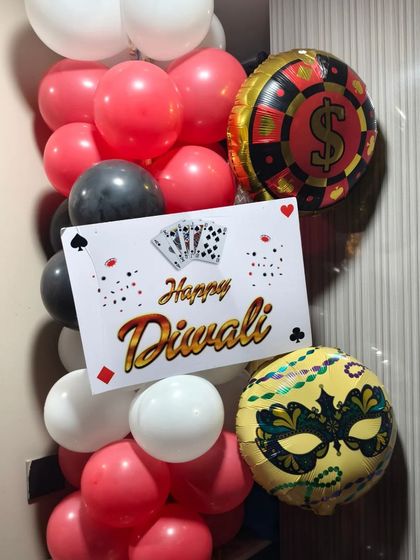 A balloon arrangement for a Diwali card party, featuring casino-themed foil balloons and a "Happy Diwali" sign.