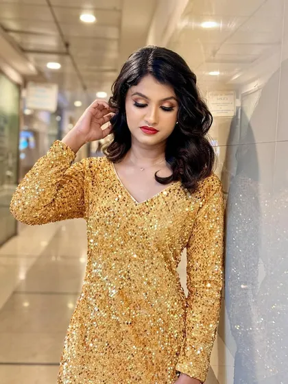 A full-length shot of the golden sequin dress. The makeup is designed to be just as sparkly and eye-catching as the outfit.