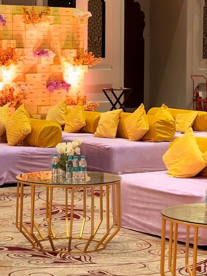 Comfortable and stylish low seating for a Haldi ceremony. We used plush lilac mattresses topped with bright yellow cushions, arranged in front of a creative backdrop made of stacked boxes and flowers.