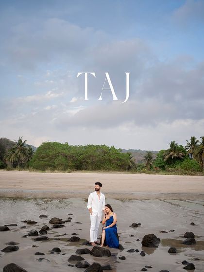 A wide shot showing the couple against the beautiful coastal landscape. This image captures the scale and serenity of the location, making the couple's moment feel both intimate and epic.