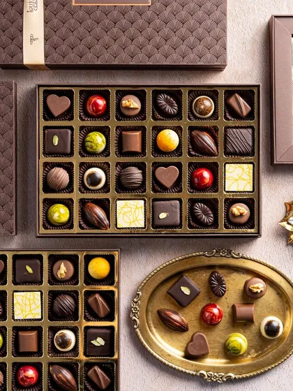 An overhead view of my artisanal Belgian chocolate praline collection, presented in elegant brown boxes of various sizes. Each chocolate is a unique piece of art, showcasing different shapes, colors, and fillings perfect for sophisticated Diwali gifting.