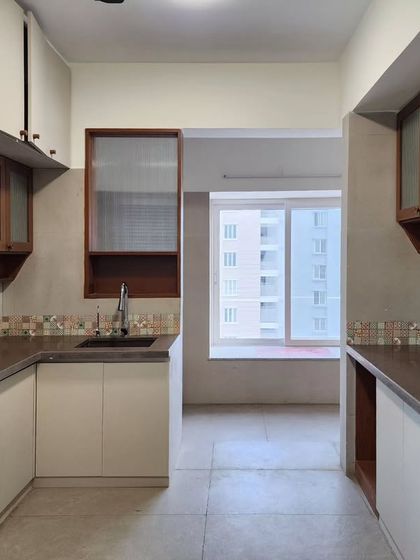 A view down a galley kitchen, designed for maximum efficiency. The combination of white lower cabinets and wood-framed upper cabinets creates a balanced look, while the patterned tile backsplash adds a decorative touch.