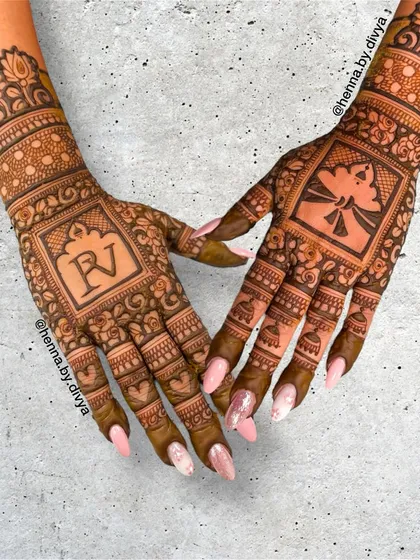 A personalized back-hand design for the bride, featuring her initial "RV" on one hand and a bride-groom motif on the other. The surrounding patterns are dense and traditional.