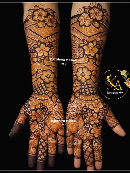 A full-arm floral mehendi with a modern twist. The design incorporates geometric chevron patterns on the arms, which contrast beautifully with the soft, shaded flowers on the hands.