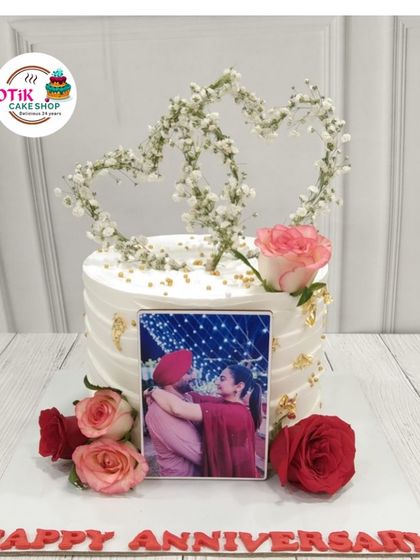 A personalized anniversary cake that tells a love story. We incorporated an edible photo of the couple, framed by heart-shaped baby's breath and fresh roses for a truly romantic touch.