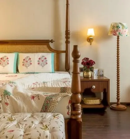 A styled shot of the classic four-poster bed. The turned wood on the posts and the matching floor lamp show a commitment to detailed craftsmanship, creating a warm and inviting bedroom atmosphere.