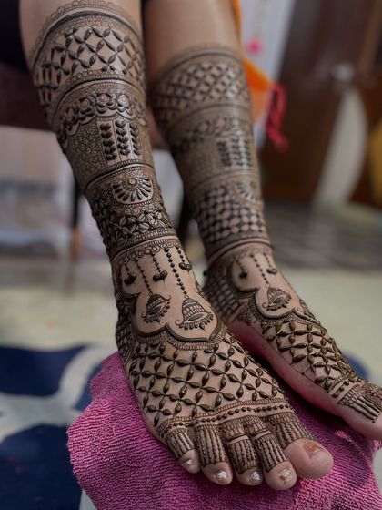 A full view of a heavy bridal foot mehandi, with patterns extending from the toes well up the shins.
