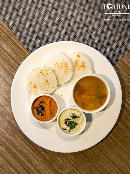 Soft and fluffy idlis served with flavorful sambar and two kinds of chutney, a staple of our South Indian breakfast offerings.