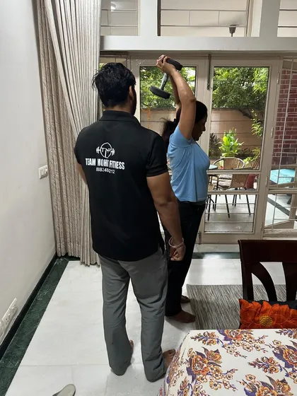 A trainer from my team guiding a client through an overhead tricep extension at home. We focus on correct form to maximize muscle engagement.
