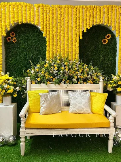 A classic Haldi setup with a modern twist. We created arches made entirely of marigolds against a green backdrop, with a clean white bench and disco balls for a touch of fun.