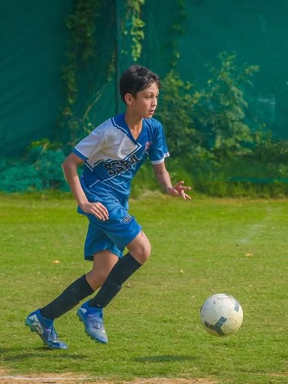 A young player dribbles confidently down the field, looking up to find a teammate and make the right pass.