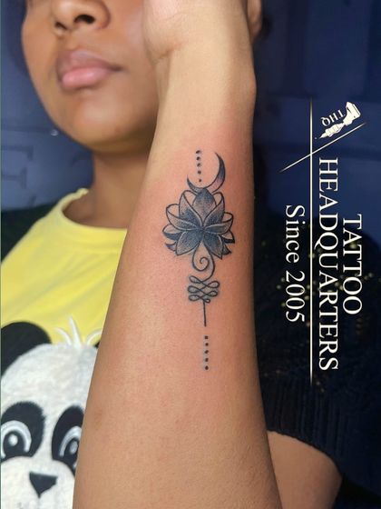 A beautiful Unalome and lotus tattoo, symbolizing the path to enlightenment, inked on the forearm.