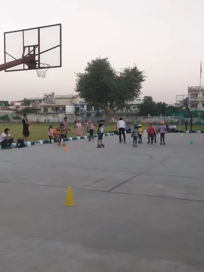 A wide view of a kids' skating session in progress on the multi-sport court. You can see parents watching from the sidelines as the children learn.