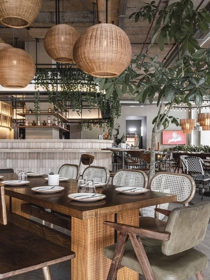 Large community tables, highlighted by clusters of woven pendant lights, create intermediate points of interest. These setups are perfect for larger groups and foster a communal dining atmosphere.