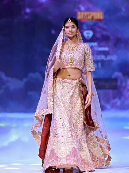 A full-length view of the pink and maroon lehenga. The sheer net dupatta is lightly embroidered, allowing the detailed work on the lehenga and choli to shine.
