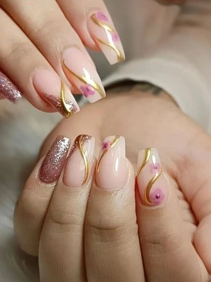 An elegant design with a nude base, rose gold glitter accents, and delicate gold swirls with tiny painted flowers.