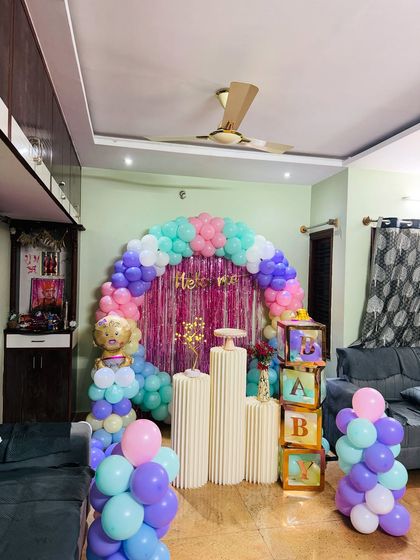 Another angle of the pastel "Welcome Baby" home decoration, showing the full balloon arch and the placement of the props and pedestals.