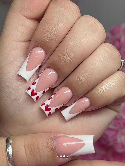 A bold Valentine's Day look with long, square-tipped nails. This set combines a V-shaped French tip with accent nails covered in red hearts.