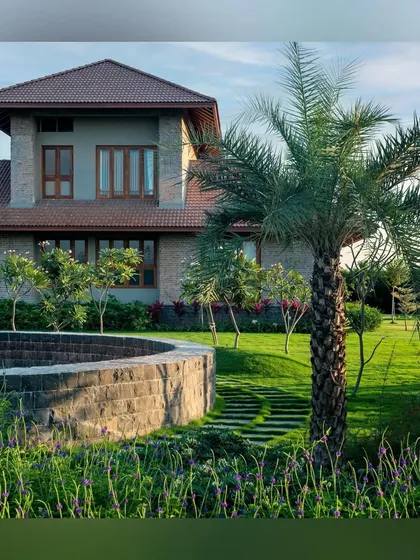 A curved stone wall and a mature palm tree are key features in the garden of the "House with Two Courts." We use natural materials and specimen plants to create points of interest and structure within a larger landscape.