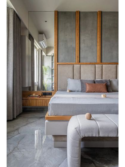 This view of the bedroom highlights the serene color palette of soft greys, natural wood, and muted blues. The design is clean and organized, with a focus on creating a restful environment through harmonious colors and textures.