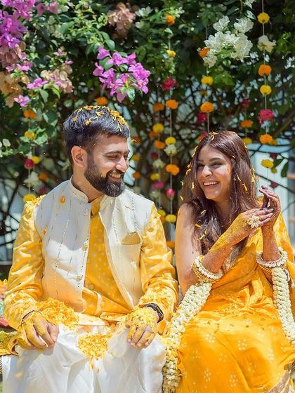 A candid moment from a Haldi ceremony in Goa. The bride and groom are covered in turmeric and flowers, sharing a laugh under the sun. It's a perfect picture of joy and celebration.