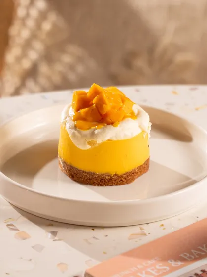 A mini mango cheesecake, looking bright and sunny. This is a perfect shot for a summer menu special.