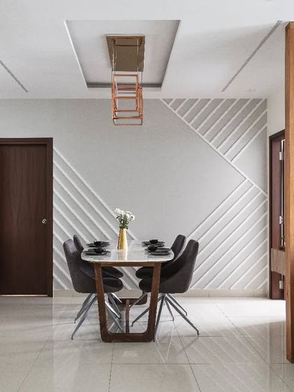This dining area is designed around the concept of 'hygge,' or cozy contentment. The feature wall with geometric molding, a simple dining set, and a wooden slat partition creates a space that feels warm, relaxed, and perfect for family meals.