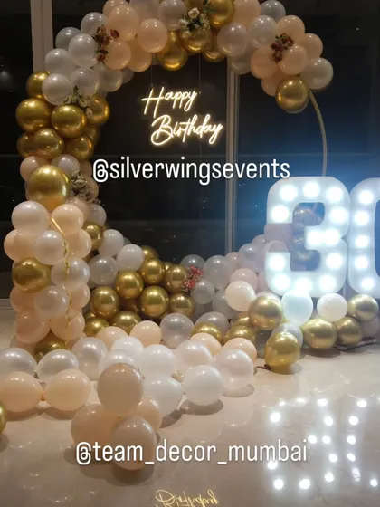 Celebrating a 30th birthday in style. This elegant setup features a circular balloon arch in pastel, white, and gold chrome, a custom neon sign, and large marquee numbers that create a perfect photo opportunity.