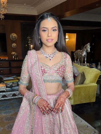 The bride looking radiant for her Mehendi ceremony, her hair styled in a simple yet elegant half-updo that lets her smile and outfit shine.