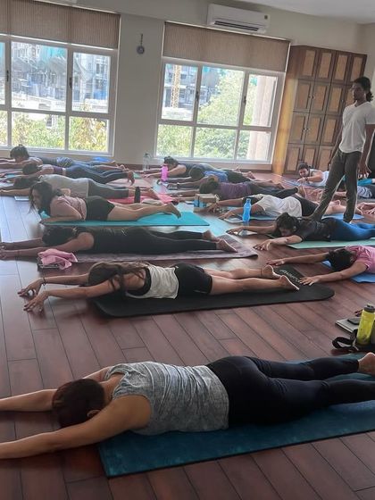 A moment of rest and integration during a masterclass. After intense practice, allowing the body to absorb the work in Savasana (Corpse Pose) is essential for recovery and growth.