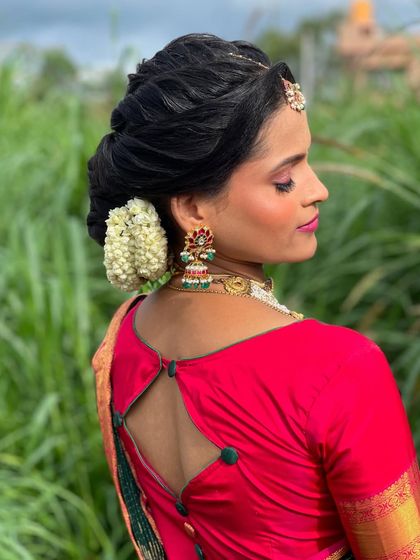 Vanitha's complete look, with her hair styled beautifully to complement her bright pink and green saree.