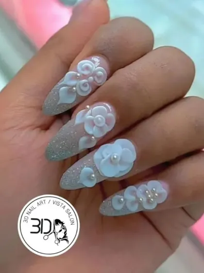 Intricate 3D floral designs on a sparkling silver glitter base. These almond-shaped nails are adorned with hand-sculpted white flowers and delicate pearl centers, creating a beautiful texture and a look perfect for brides or any formal event.
