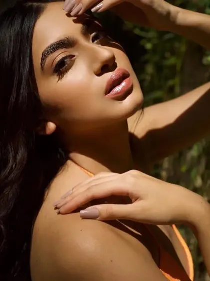 A close-up in the golden hour light. This highlights the dewy, glowing finish of the skin and the glossy texture of the lips, creating a very healthy and radiant look.