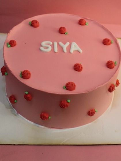 A simple and sweet cake for a naming ceremony. The delicate pink frosting and tiny red roses create a lovely design to welcome a new baby.