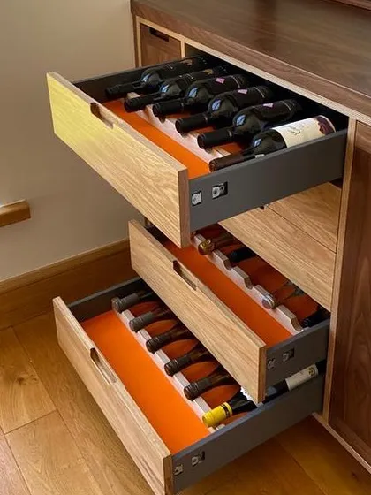 A closer look at the custom wine storage drawers. These are built with solid oak fronts and feature a vibrant orange lining for a personal touch. Each drawer is designed for easy access and secure storage of your wine collection.