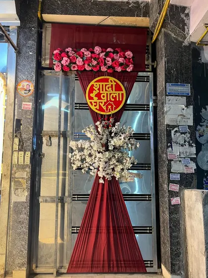 It's all in the details. A custom 'Shadi Wala Ghar' sign adorns the main entrance, featuring red drapes and floral arrangements to set a festive and welcoming tone from the moment guests arrive.