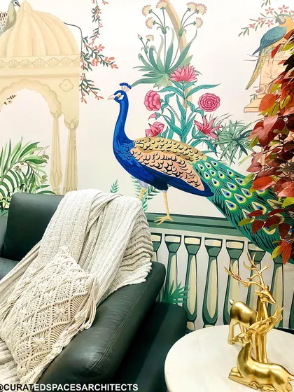 A close-up of the nature-inspired living room, showing how the rich texture of the leather sofa contrasts beautifully with the soft throw and the vibrant peacock wallpaper.