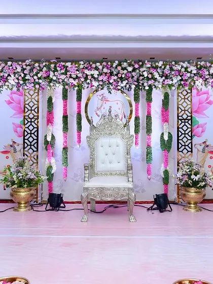 We designed this grand stage for a traditional baby shower, or Seemantham, featuring a regal silver throne for the mom-to-be. The backdrop includes sacred cow and lotus motifs, framed by lush floral garlands in pink and white, creating a truly divine atmosphere.