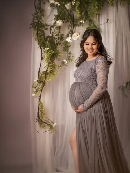 A serene portrait of the mom-to-be cradling her bump. The soft light and the delicate floral background create a peaceful and beautiful atmosphere.