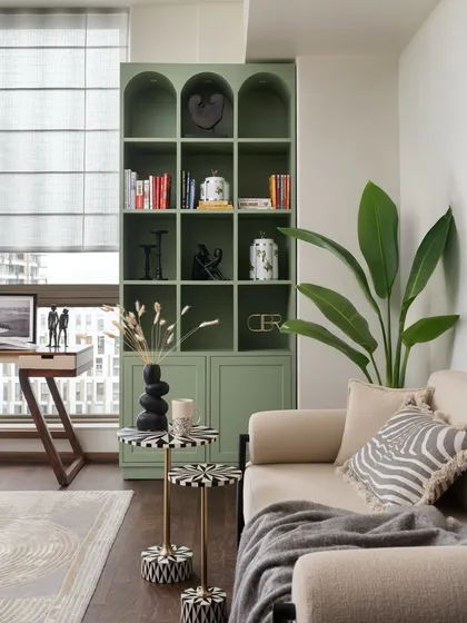 Details are what transform a house into a home. This corner showcases how I blend function with beauty, using a custom sage green bookshelf to provide storage while acting as a statement piece. The mix of textures, from the smooth finish of the cabinetry to the organic form of the plant, adds layers of visual interest.